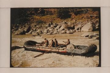 A boloney boat of the Hatch collection driving toward a rock in Hells Half Mile. Jack Collier, oarsman at left; Dale; passengers are Bill McLand and Ed Richardson