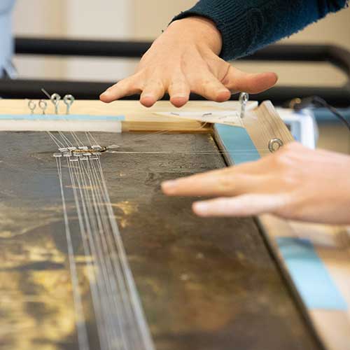Conservator using a stretching device to repair painting