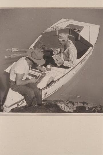 Repairing the sadiron "JOAN" after damage at Rapid #24 in Cataract Canyon. Nevills wears his cap backwards and his pajama top