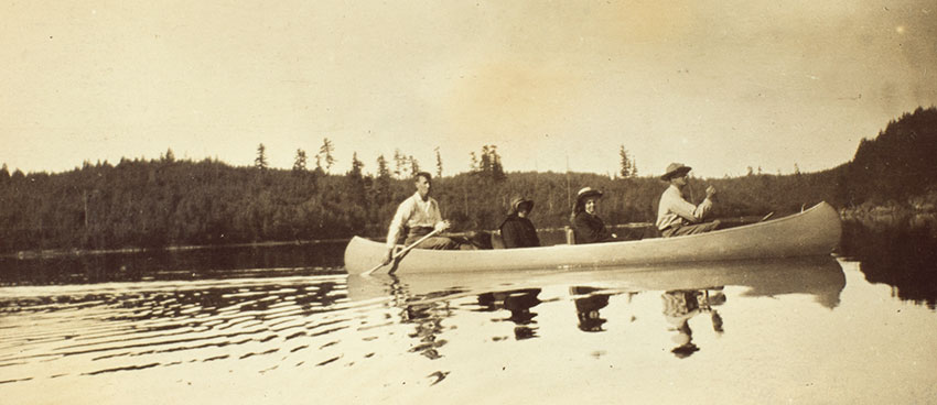 The label for this image in one of the Turners’ photograph albums of their 1908 canoe trip reads: “Kahnipiminanikok / Dow and the Turners en route.” “Kahnipiminanikok” is the Ojibwe name of Kawnipi Lake in Ontario, Canada. Seated in the bow seat is historian Frederick Jackson Turner (far right); behind him sits his wife, Caroline Mae Turner (second from right) and their daughter, Dorothy K. Turner (third from right). Jesse Dow (far left), one of the trip guides, sits in the stern seat, steering the canoe. Unidentified photographer. The Huntington Library, Art Collections, and Botanical Gardens. The label for this image in one of the Turners’ photograph albums of their 1908 canoe trip reads: “Kahnipiminanikok / Dow and the Turners en route.” “Kahnipiminanikok” is the Ojibwe name of Kawnipi Lake in Ontario, Canada. Seated in the bow seat is historian Frederick Jackson Turner (far right); behind him sits his wife, Caroline Mae Turner (second from right) and their daughter, Dorothy K. Turner (third from right). Jesse Dow (far left), one of the trip guides, sits in the stern seat, steering the canoe. Unidentified photographer. The Huntington Library, Art Collections, and Botanical Gardens.